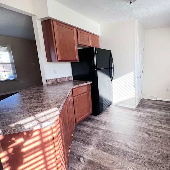 a kitchen with brown cabinets and a black refrigerator.
