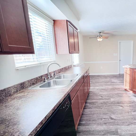 a kitchen with brown cabinets and a black fridge.