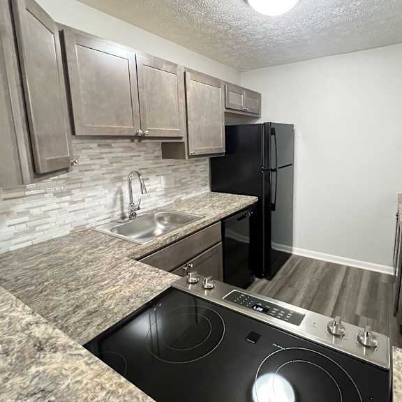 a kitchen with granite counter tops and a black stove and refrigerator at fox run apartments, cincinnati