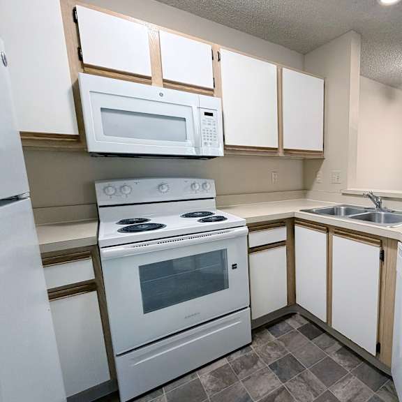 a kitchen with white appliances and wooden cabinets.