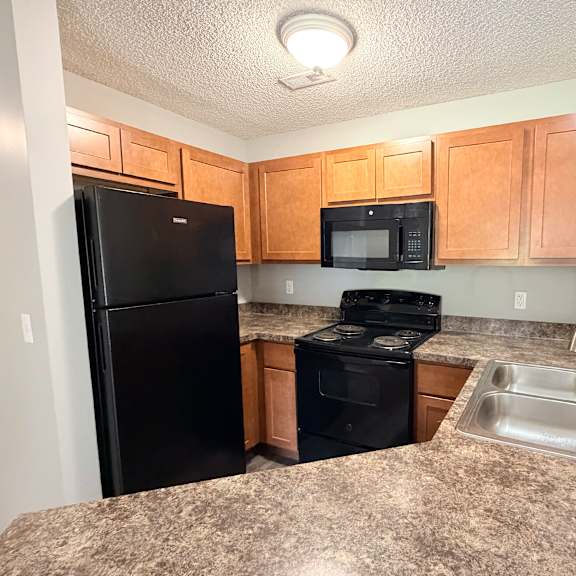 a kitchen with black appliances and wooden cabinets.
