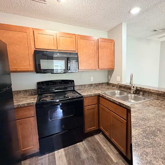 a kitchen with black appliances and wooden cabinets.