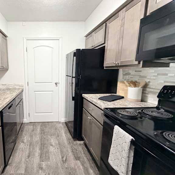 a kitchen with black appliances and wooden cabinets.
