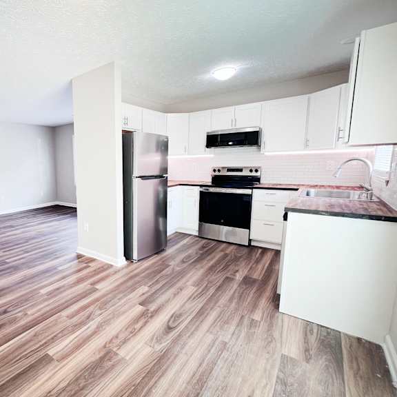 a kitchen with a refrigerator, oven, and stove top.