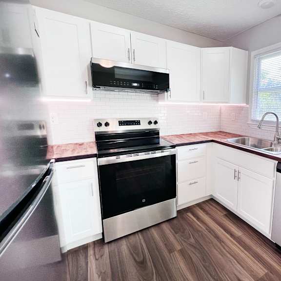 a kitchen with white cabinets and stainless steel appliances.