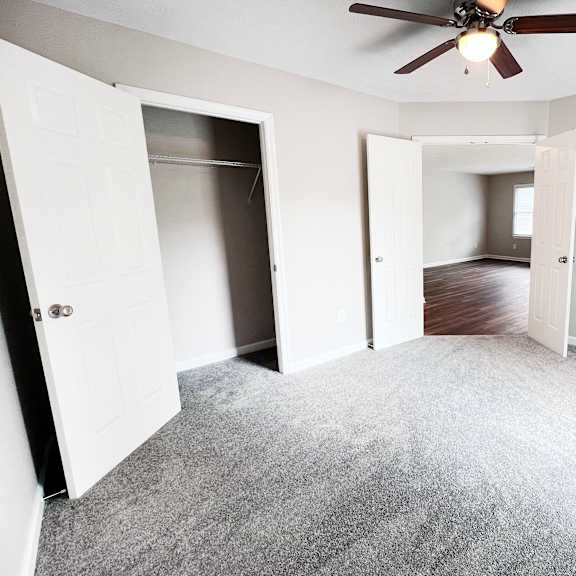 a room with a ceiling fan and carpeted floor.