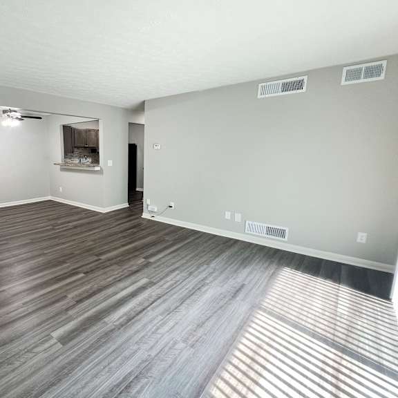 an empty living room with wood flooring and a white door at fox run apartments, cincinnati