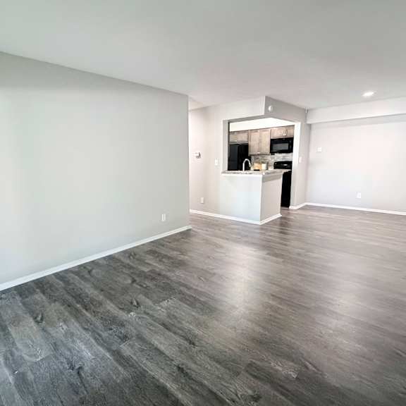 a spacious room with wooden flooring and white walls.