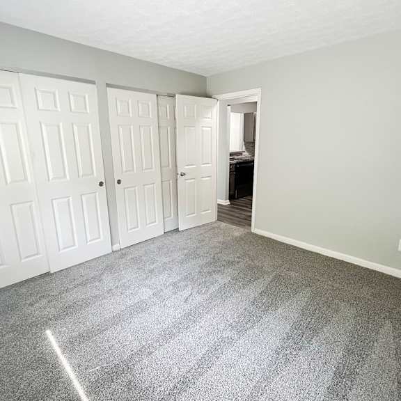 an empty bedroom with white doors and carpeting at fox run apartments, cincinnati