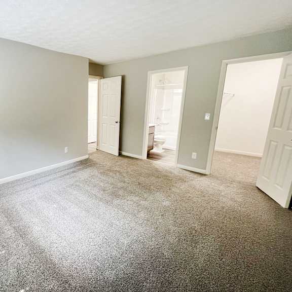 an empty living room with carpet and a door to a bathroom at fox run apartments, cincinnati
