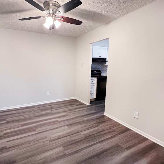 a room with a ceiling fan and wooden flooring.