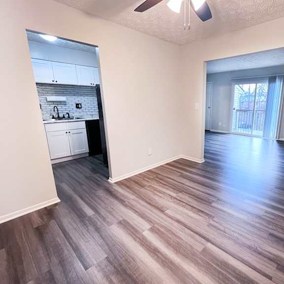 a room with a ceiling fan and wooden flooring.