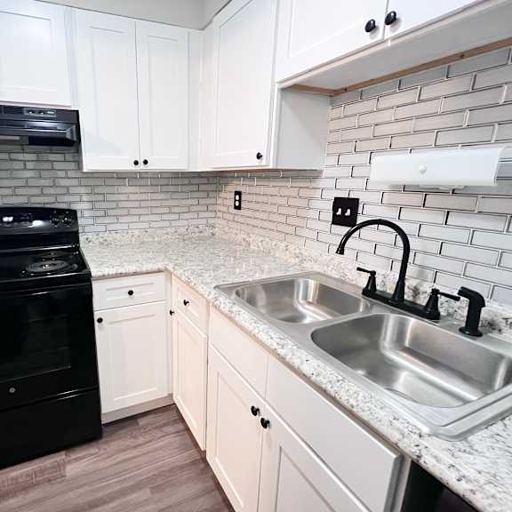 a black oven sits in a kitchen with white cabinets and a marble countertop.