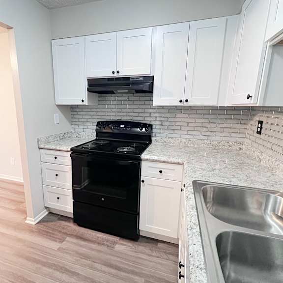 a kitchen with white cabinets and a black dishwasher.