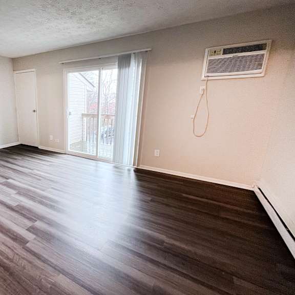 a room with wooden flooring and a window with blinds.
