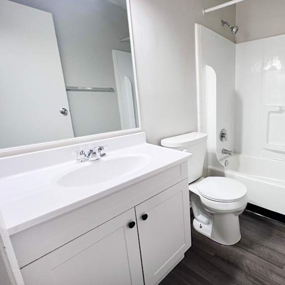 a white bathroom with a toilet, sink, and bathtub.