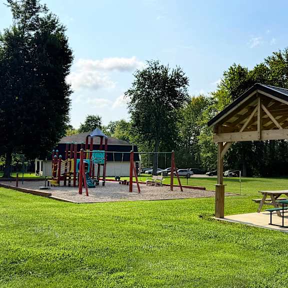 a playground with a swing set and picnic tables.