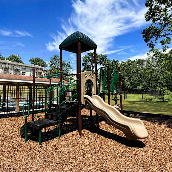 a playground with a slide and a green roofed structure.