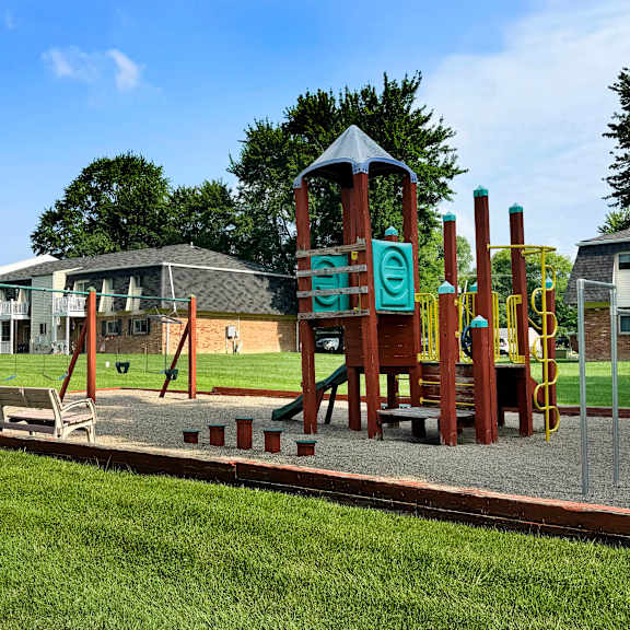 a playground with a wooden swing set and a green slide.