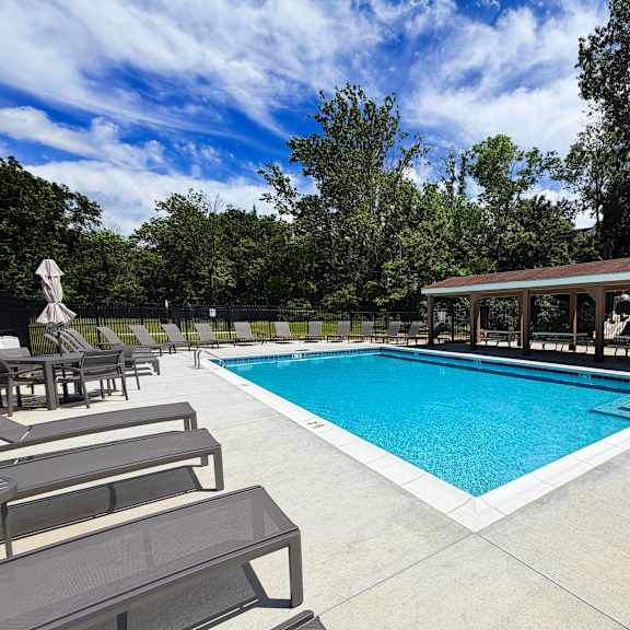 a pool with a sun lounger and a small building.