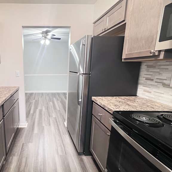 a kitchen with a black refrigerator and a stove top oven.