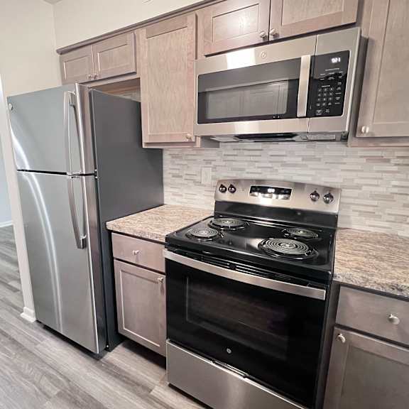 a kitchen with a stove, refrigerator, and microwave.