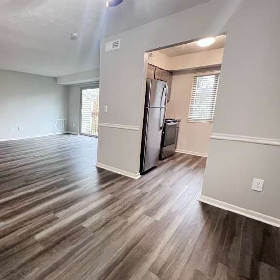 a room with wooden flooring and a refrigerator in the corner.