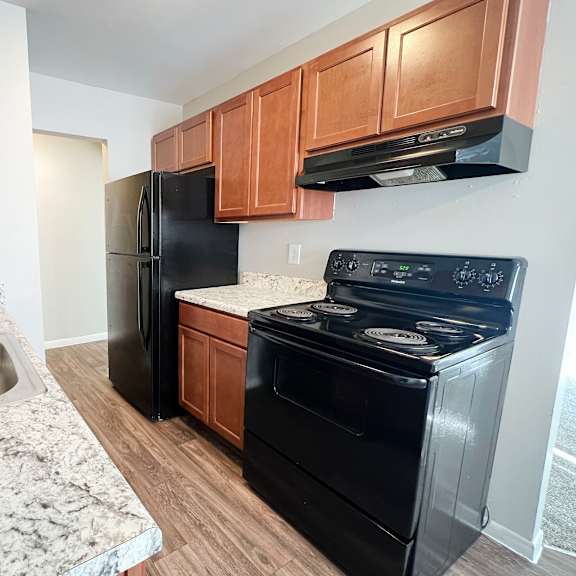 a black refrigerator and stove in a kitchen with wooden cabinets.