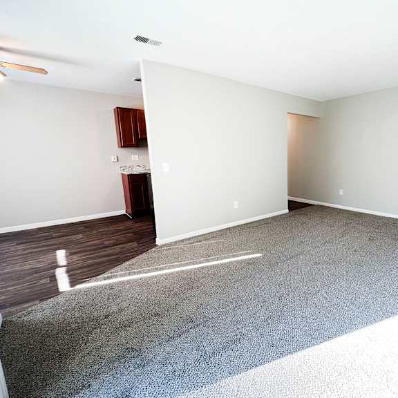 a spacious room with a carpeted floor and a ceiling fan.
