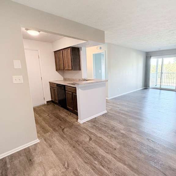 a spacious living room with a fireplace and a kitchen area in the background.