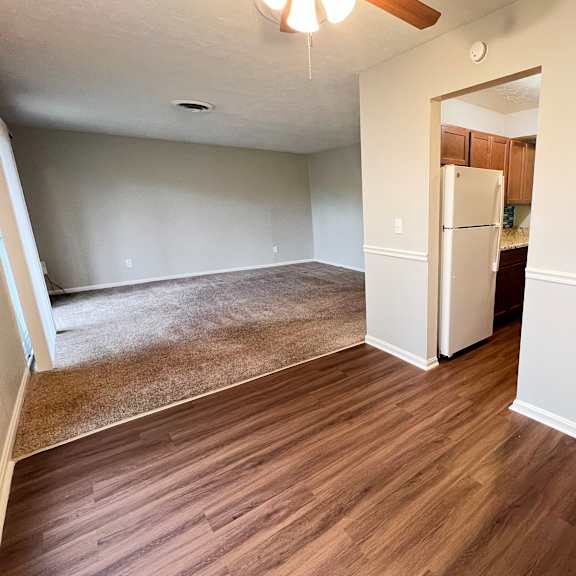 a room with a brown floor and a white fridge.