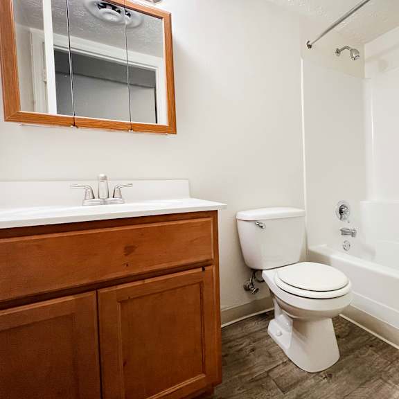a white toilet sits in a bathroom next to a sink and a bathtub.