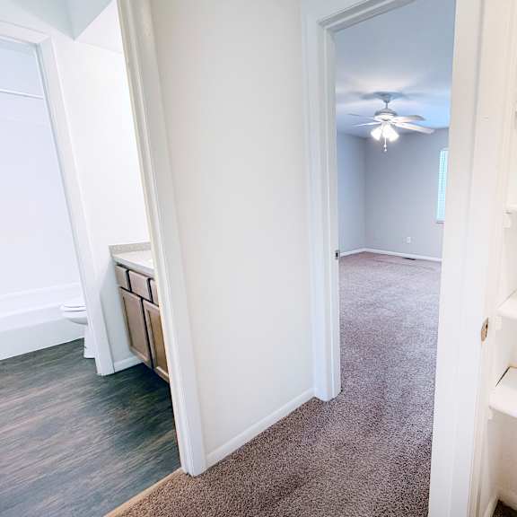 a white shelving unit is in a room with a carpeted floor and a ceiling fan.