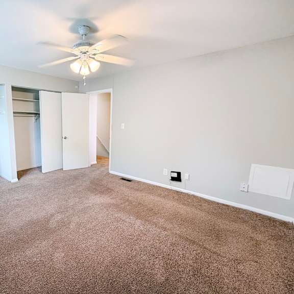 a room with a ceiling fan and carpeted floor.