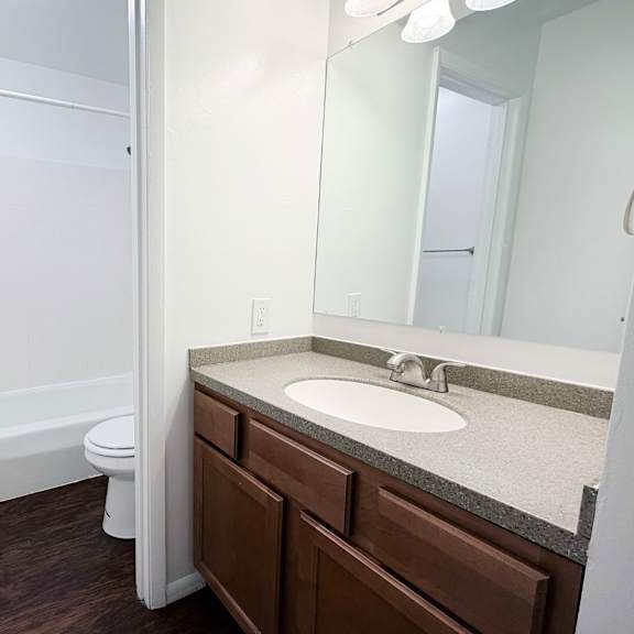 a white bathroom with a toilet, sink, and mirror.