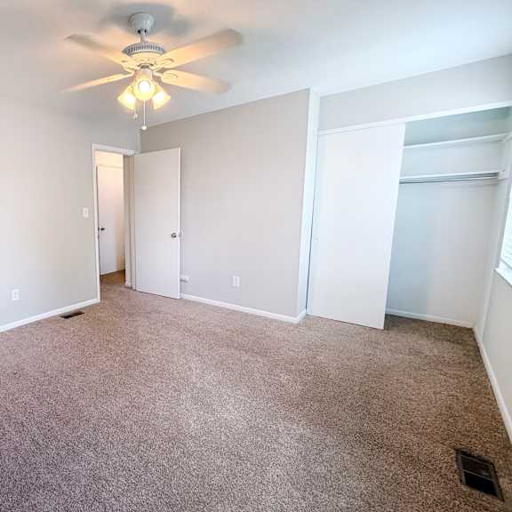 a room with a ceiling fan and carpeted floor.