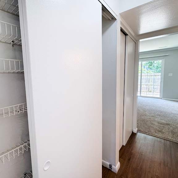 a white refrigerator with empty shelves in a room with a door leading to a hallway.