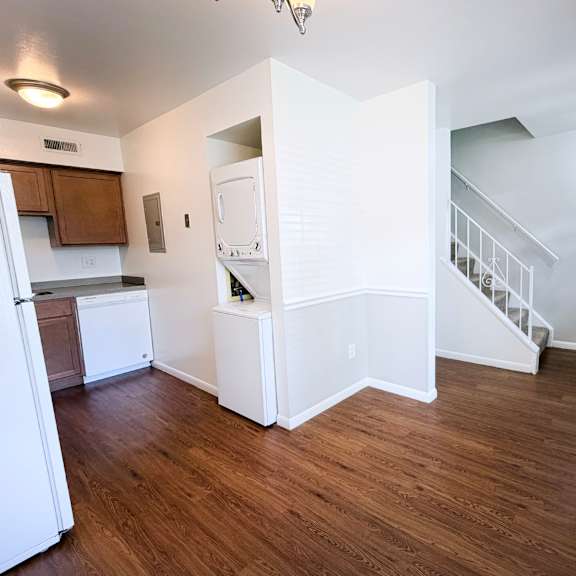 a kitchen with white appliances and wooden floors.