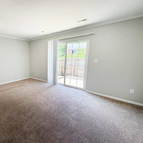 a room with a carpeted floor and a sliding glass door leading outside.