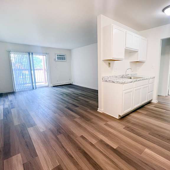a kitchen with white cabinets and a wooden floor.