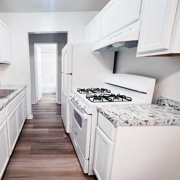 a kitchen with white cabinets and granite countertops.