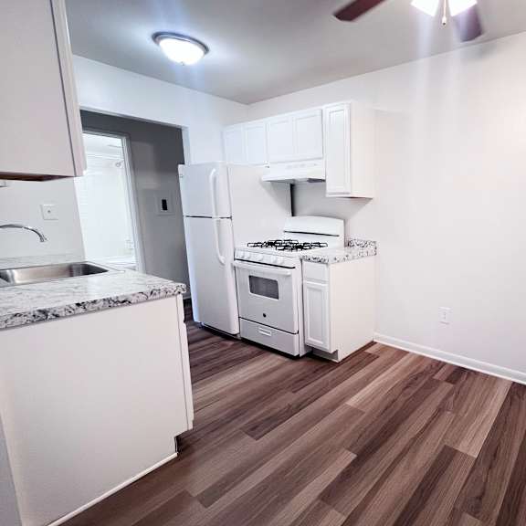 a kitchen with white appliances and wood flooring.