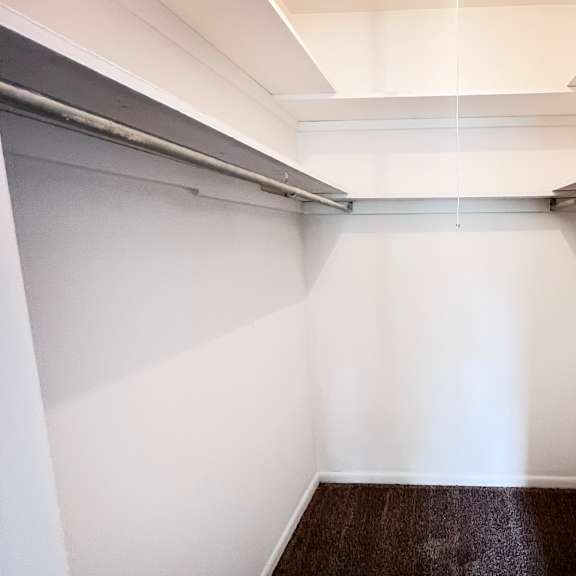 a long, narrow hallway with white walls and a brown carpeted floor.
