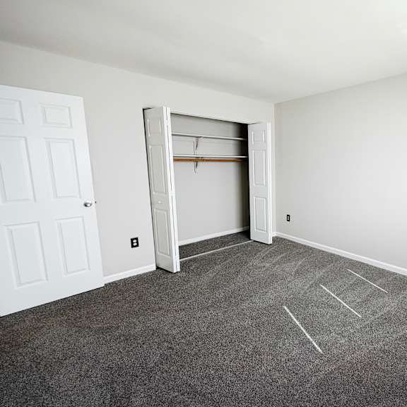 a room with a grey carpet and a white door.