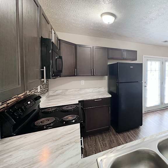 a kitchen with a black refrigerator and stove top oven.