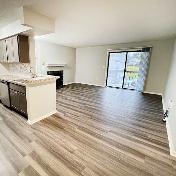 an empty living room and kitchen with wood flooring  at deercross apartments, ohio