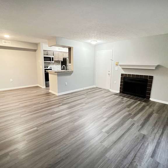 an empty living room with a fireplace and wooden floors  at deercross apartments, cincinnati