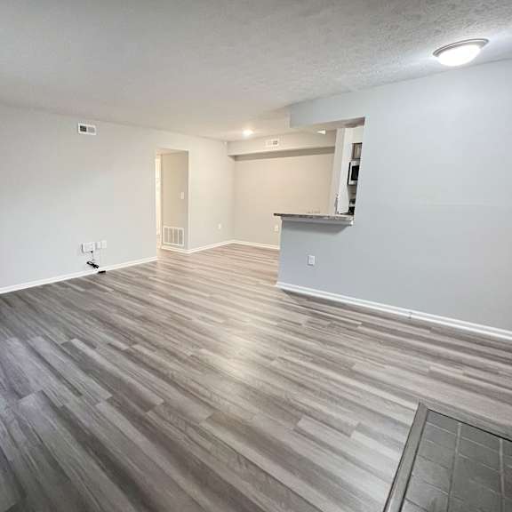 the living room and dining room of an apartment with wood flooring  at deercross apartments, ohio