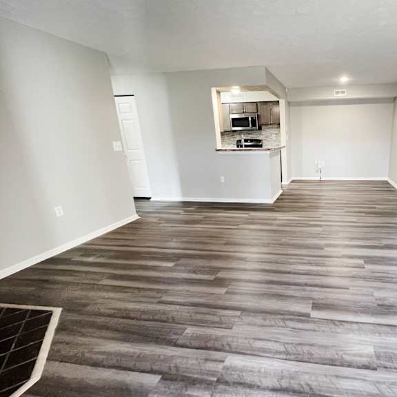 an empty living room with wood flooring and a kitchen  at deercross apartments, cincinnati