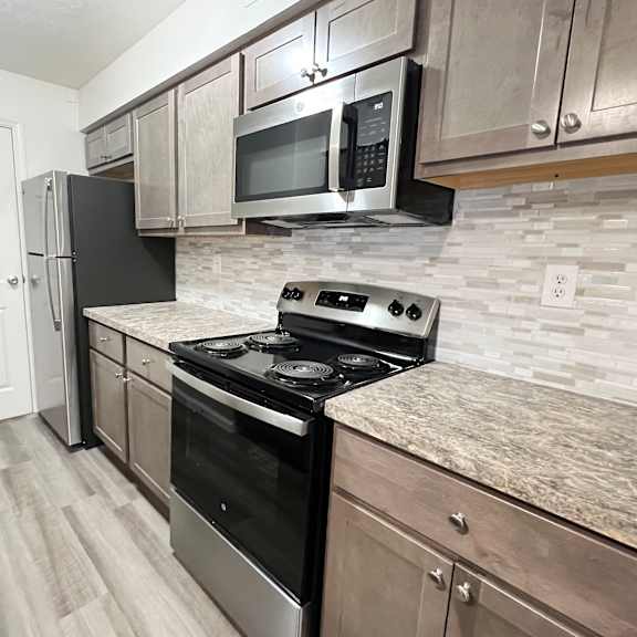 an updated kitchen with stainless steel appliances and marble counter tops  at deercross apartments, ohio